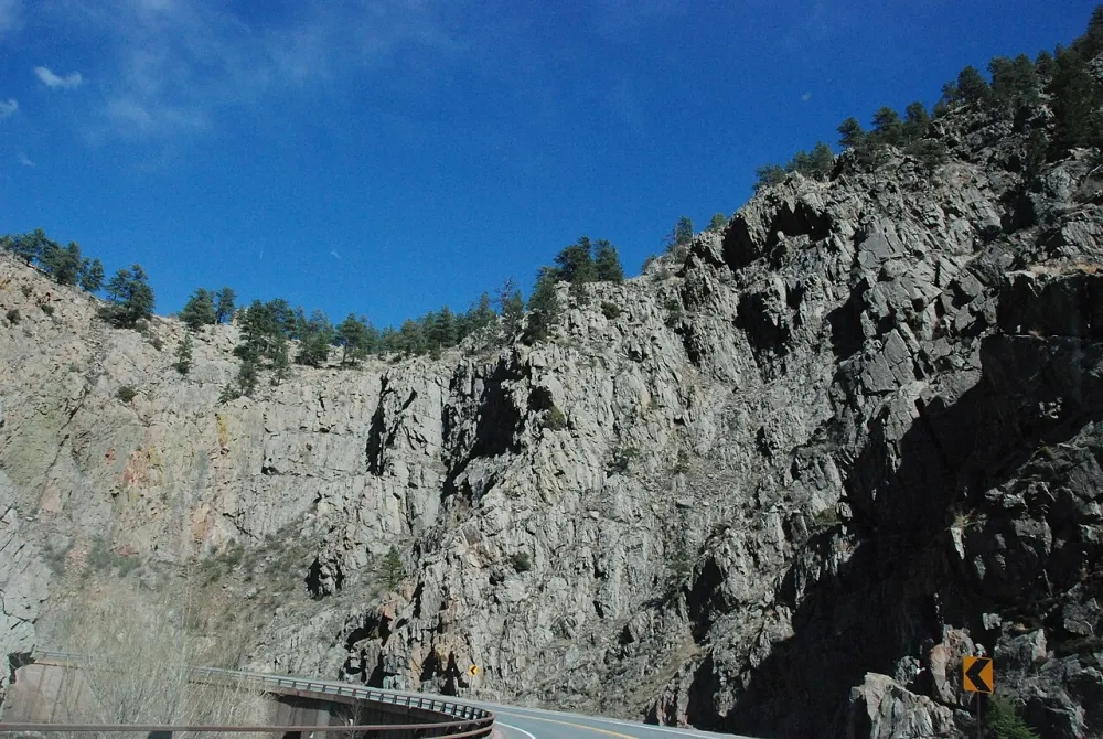 Sheer grey rock walls rising above a bend of the canyon road