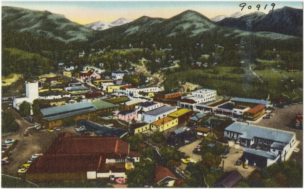 A hand-tinted vintage postcard view over the village of Estes Park with mountains behind