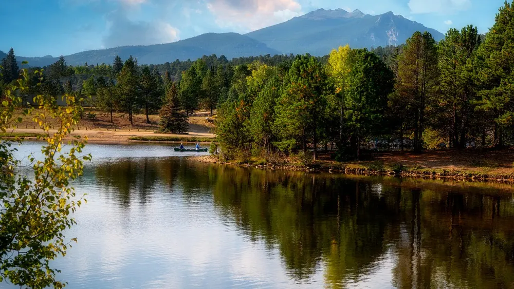 Two people canoeing on Lake Estes with pines and mountains behind